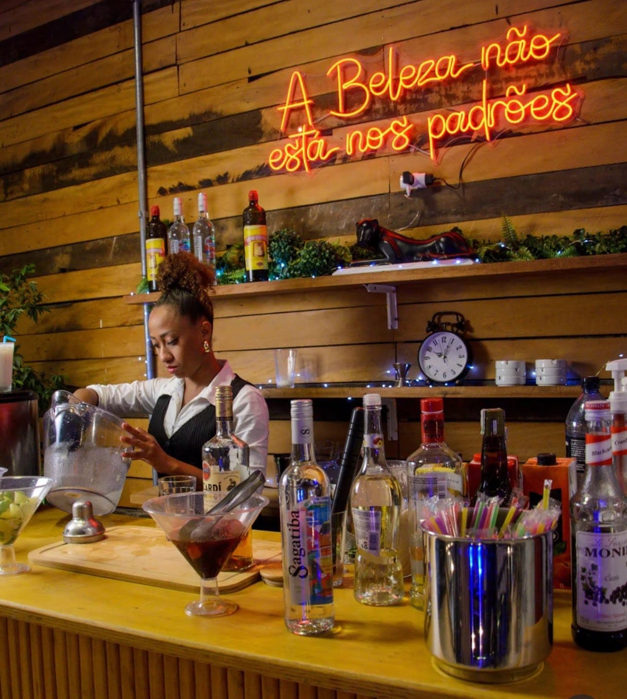 Amanda trabalhando no bar com neon ao fundo