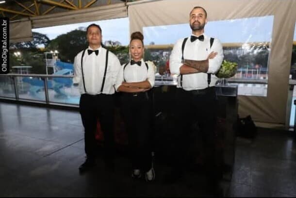 Três bartenders uniformizados de braços cruzados
